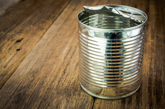 Tin can for food on wooden background with place for your text