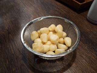 peeled garlic in a sieve on wood table