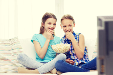 Obraz na płótnie Canvas happy girls with popcorn watching tv at home