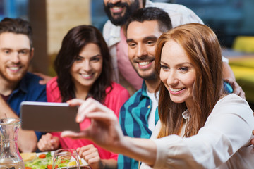 friends taking selfie by smartphone at restaurant