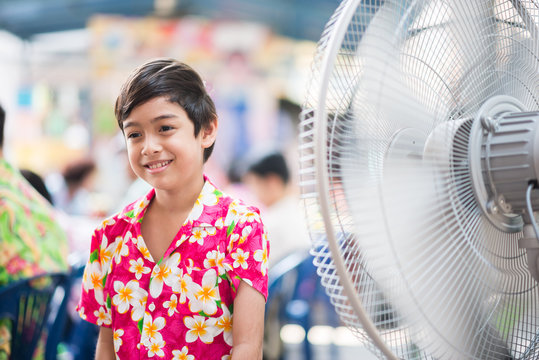 Little Boy In Front Of Electric Fan In The Summer Hot Time