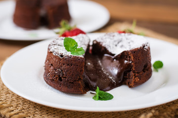 Chocolate fondant (cupcake) with strawberries and powdered sugar