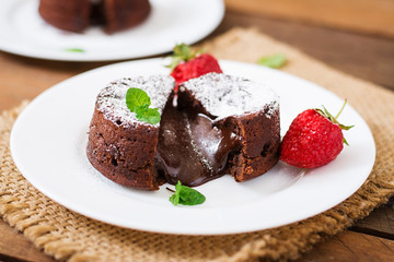 Chocolate fondant (cupcake) with strawberries and powdered sugar