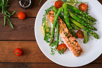 Baked salmon garnished with asparagus and tomatoes with herbs. Top view