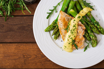 Baked chicken garnished with asparagus and herbs. Top view