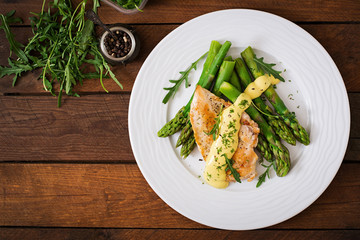Baked chicken garnished with asparagus and herbs. Top view