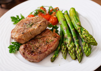 Barbecue grilled beef steak meat with asparagus and tomatoes.