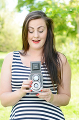 Beautiful young woman with an old camera