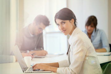 Obraz premium Businesswoman working on laptop, shared workspace