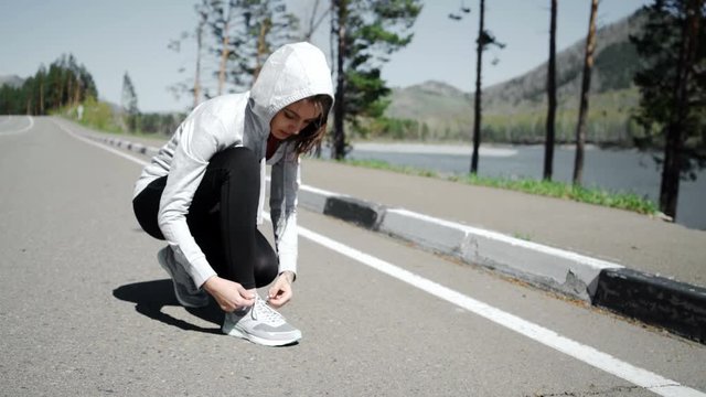 woman tying the laces on her running shoes while standing