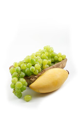 A Mango and Green Grapes on Wood Plate Isolated, white background