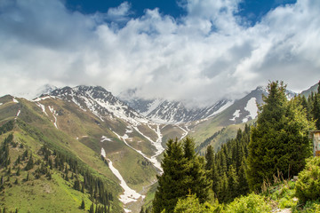 Fototapeta na wymiar Beautiful mountain landscape. Snowy peaks, green fields and heav