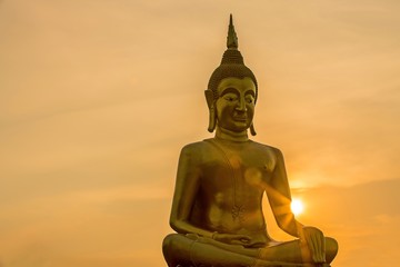 The big golden buddha statue and beautiful  twilight sky with sunset 
