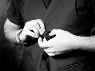 Young man adjusting his vest button.