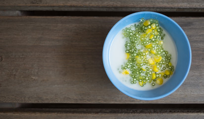 Tapioca pudding or Sakoo (Thai dessert) with coconut milk on wood table (Selective focus)