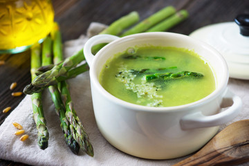 Creamy asparagus soup on wooden background