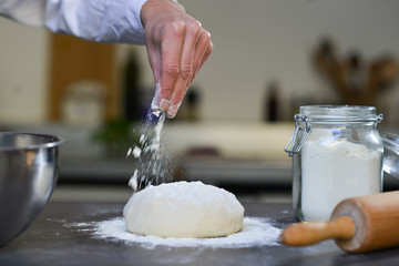 Hand sprinkle flour dough in kitchen