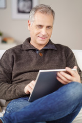 mann sitzt auf dem sofa und liest am tablet