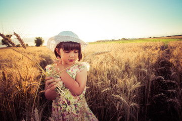 Little girl with white hat in a wheat field