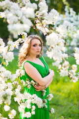 Naklejka premium Beautiful happy young woman in spring blossoming garden