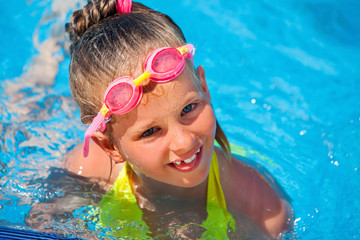 Portrait of child girl wearing googles on water slide at aquapark . Summer water holiday reacriation . Outdoor.