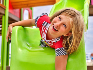 Fototapeta na wymiar Child girl upside down on park playground game. Slippery dip girl.
