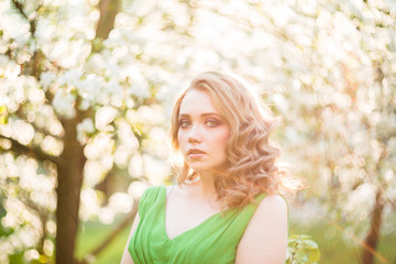 Fototapeta premium beautiful young blond woman standing beside a blossoming Apple tree