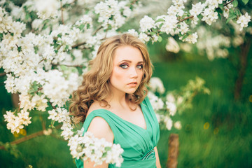 Fototapeta premium Beautiful happy young woman in spring blossoming garden