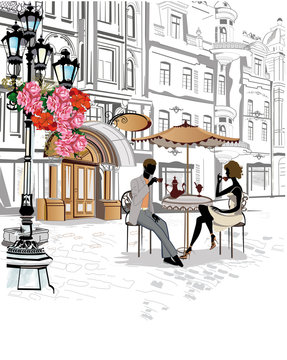 Man and woman sitting and drinking coffee in a street cafe. Background decorated with flowers, old town view.