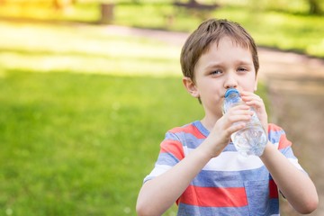 boy drinking mineral water from the plastic bottle