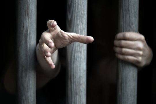 prisoner behind wooden bars begging for help