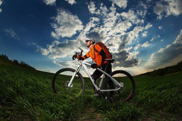 biker in orange jersey riding on green summer field