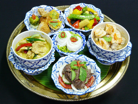 Thai food set menu - mix appetizers, green curry with chicken, grilled beef salad, spicy soup with shrimps, stir fried vegetables and rice noodles