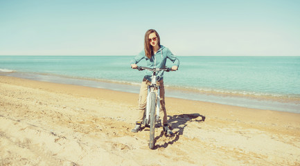 Fototapeta premium Girl with bicycle walking on beach
