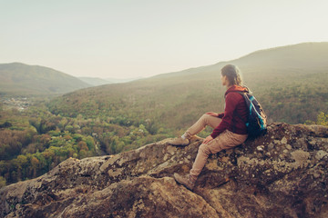 Fototapeta premium Traveler sitting on peak of rock