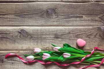 Pink tulips and gift box with rosy ribbon on a  grunge wooden ba