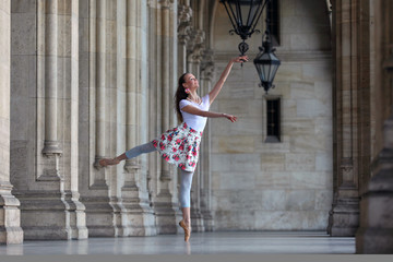 Beautiful ballerina on the street dancing the pose petit arabesque