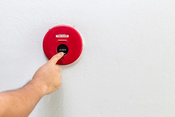 Hand with finger pressing red fire alarm on the wall