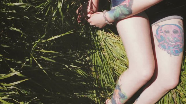 Beautiful woman with tattoos sitting on the grass