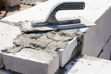 Mason float and mortar on lightweight concrete blocks. Concept for construction site