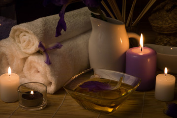 Close-up. Spa still life. Sea salt bath, massage oil, candles, flowers and towels. Body Oil. Iris flowers.