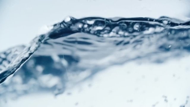 Close up of plastic straw stirring sparkling water; it splashing and waving