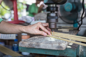 Thai women drill the hole on bamboo machine