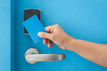 Obraz premium Hand holding blue hotel keycard in front of electric door