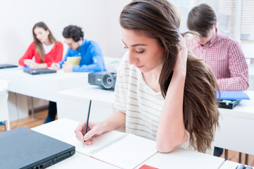 Student woman writing test in seminar room of university