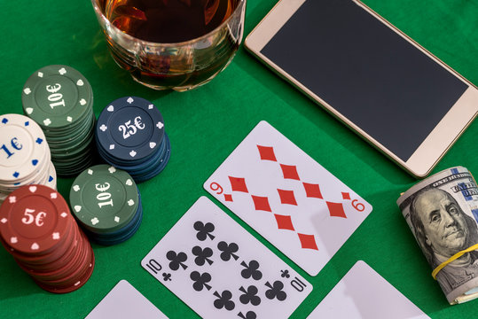 casino chips for gambling, cognac and playing cards, money and phone  on green