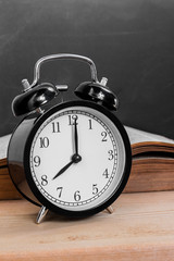 Still life of vintage alarm clock and old open book on wood tabl