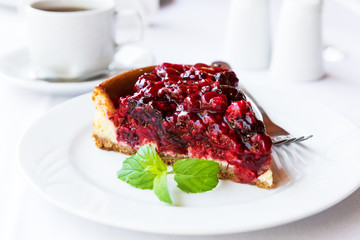 Wild berries cake with green mint on plate with fork