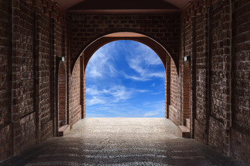 Walkway tunnel made by red brick and view of blue sky
