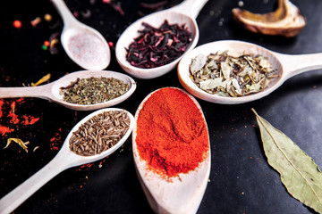 spice in wood spoon on a black background. food